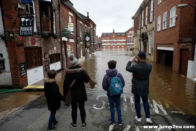 英格兰北部约克，人们站在被洪水阻断的道路旁。（图片来源：新华社）